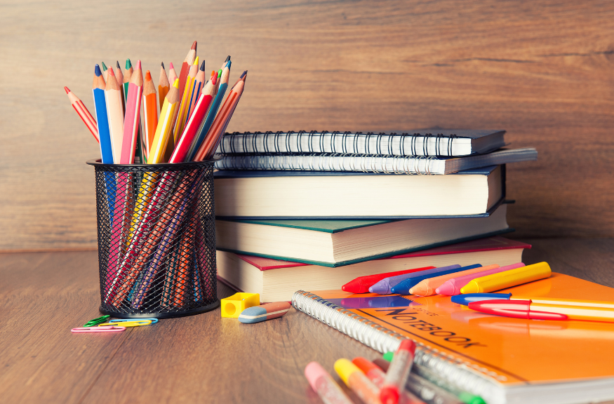 A photo of different school supplies like notebooks, pens, pencil, books, eraser, clips and crayons